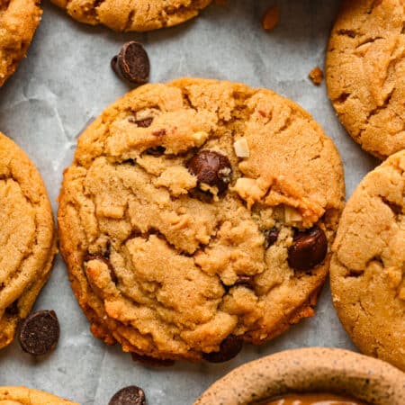 A peanut butter chocolate chip cookie surrounded by cookies.