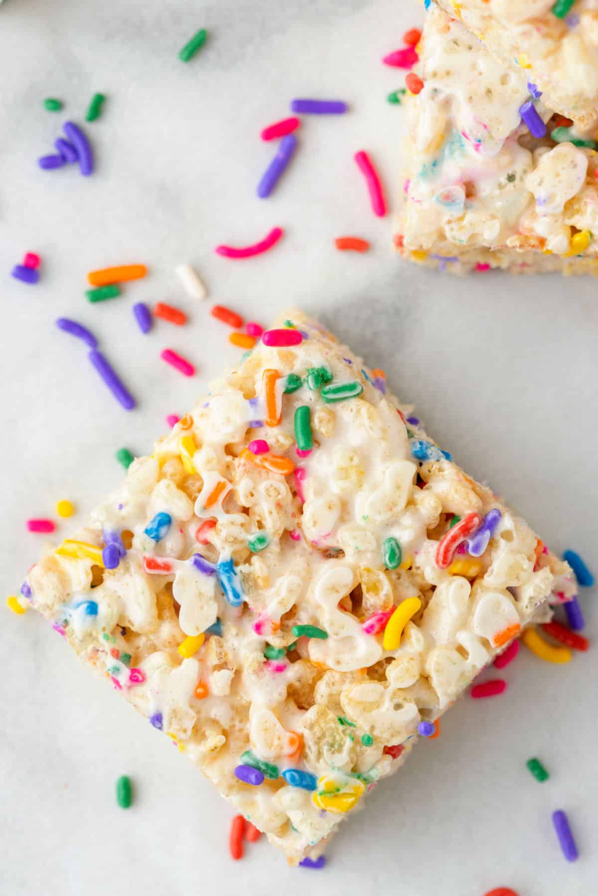 A funfetti rice krispie treat surrounded by rainbow sprinkles.