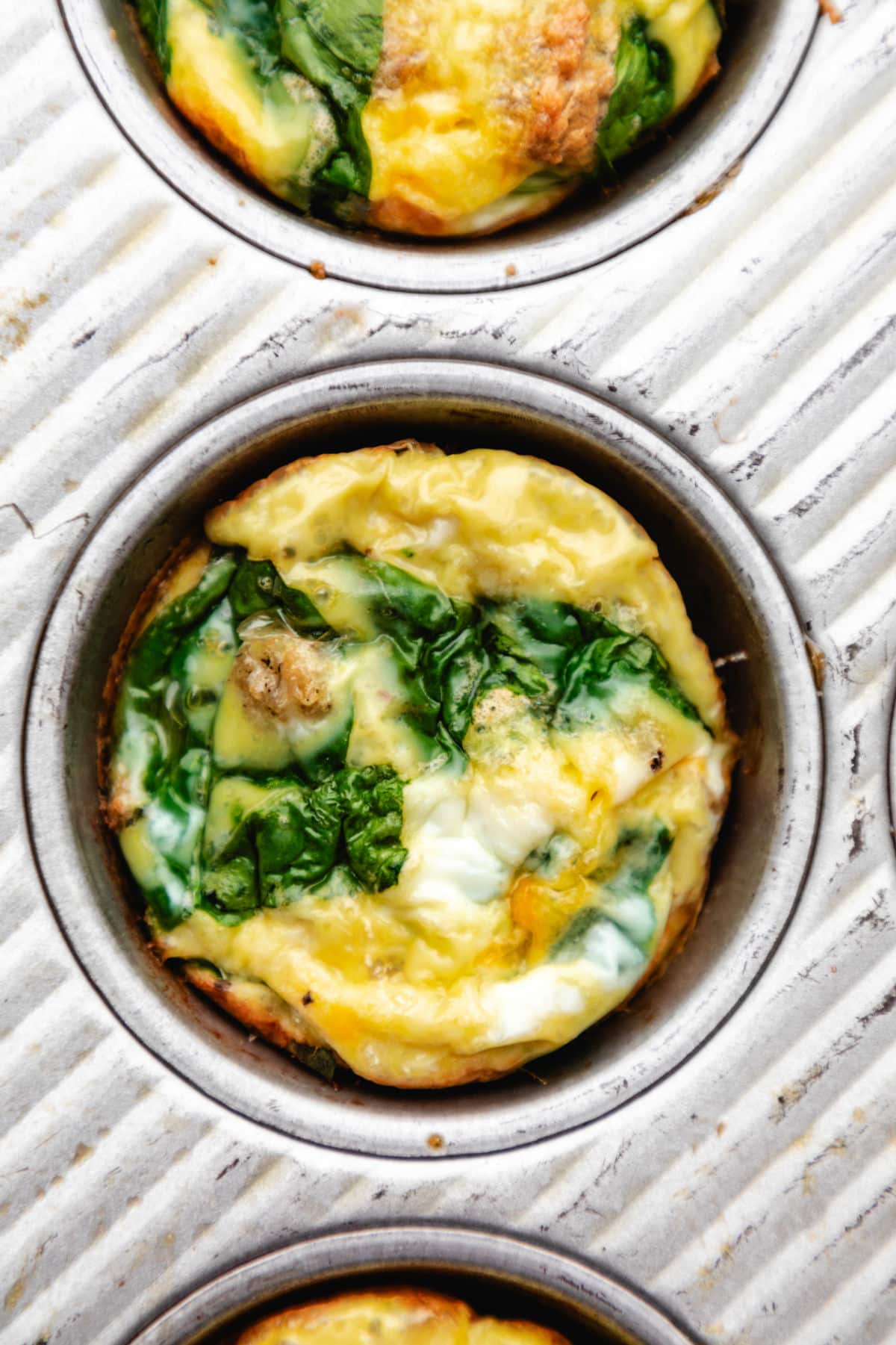 A baked sausage egg muffin in a muffin tin. 