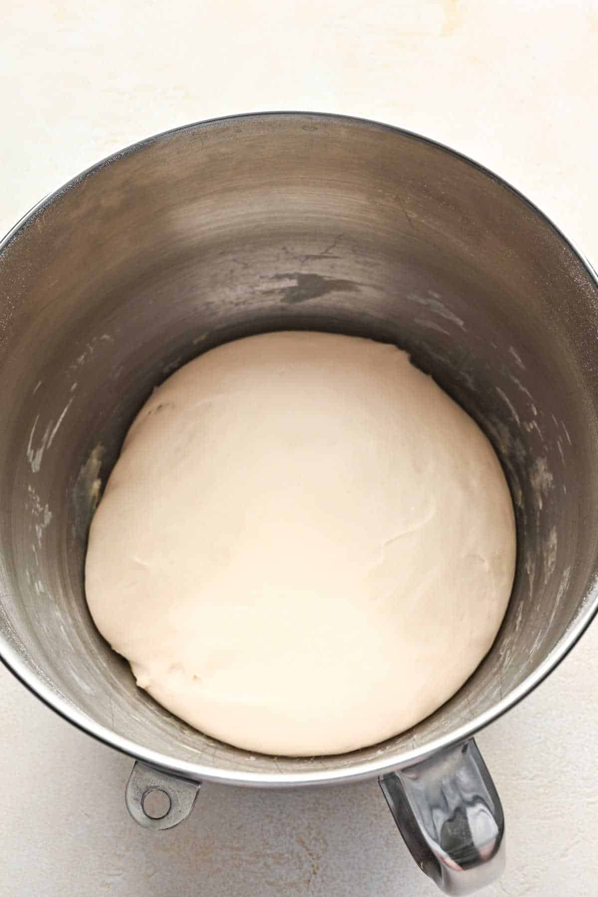 Risen breadstick dough in a silver mixing bowl. 