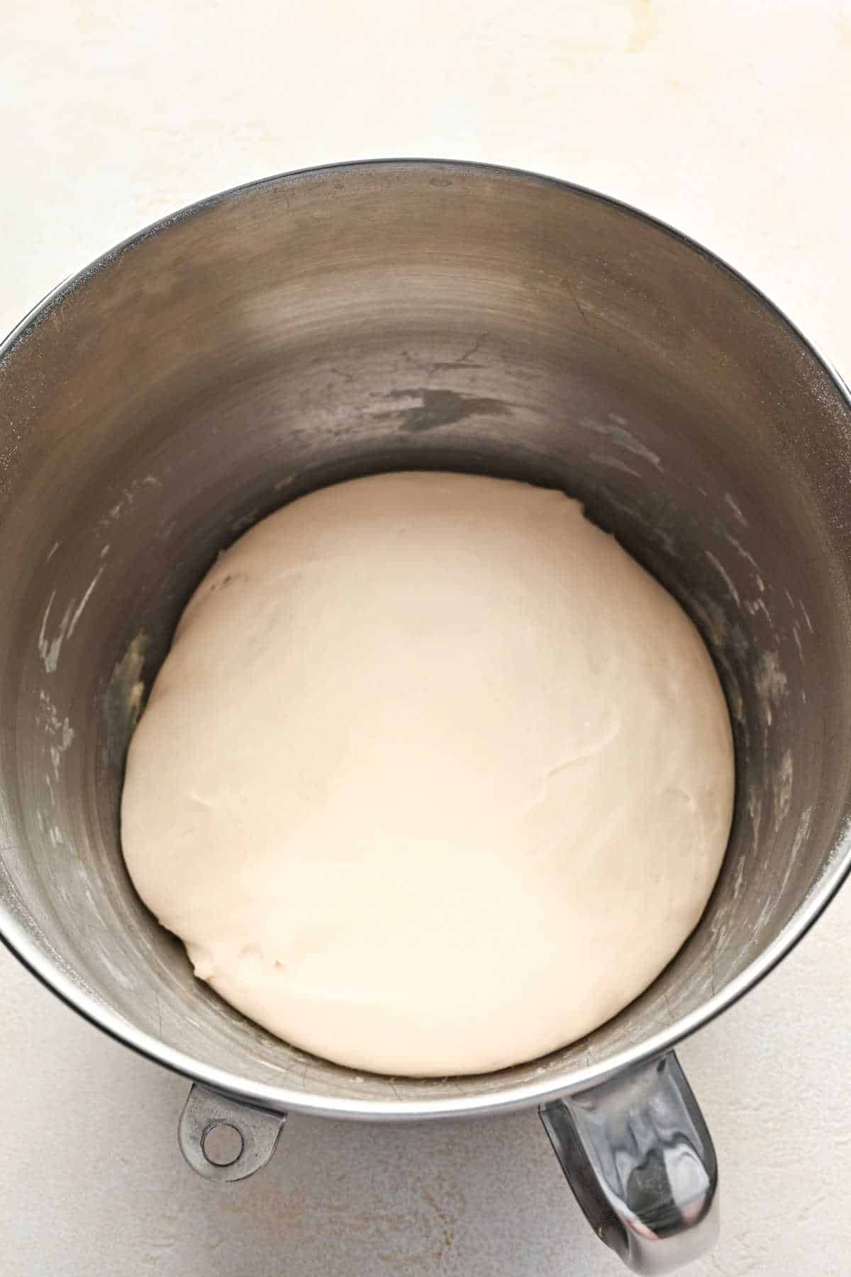 Risen breadstick dough in a silver mixing bowl.