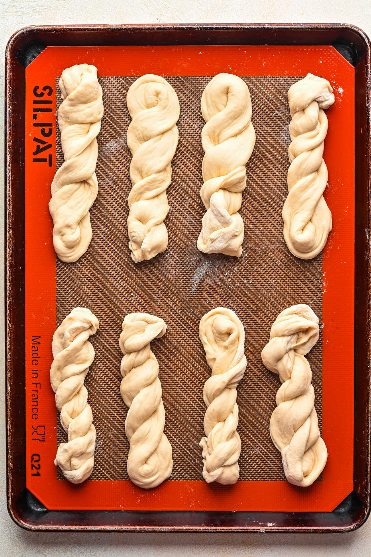 Twisted unbaked breadsticks on a baking sheet.