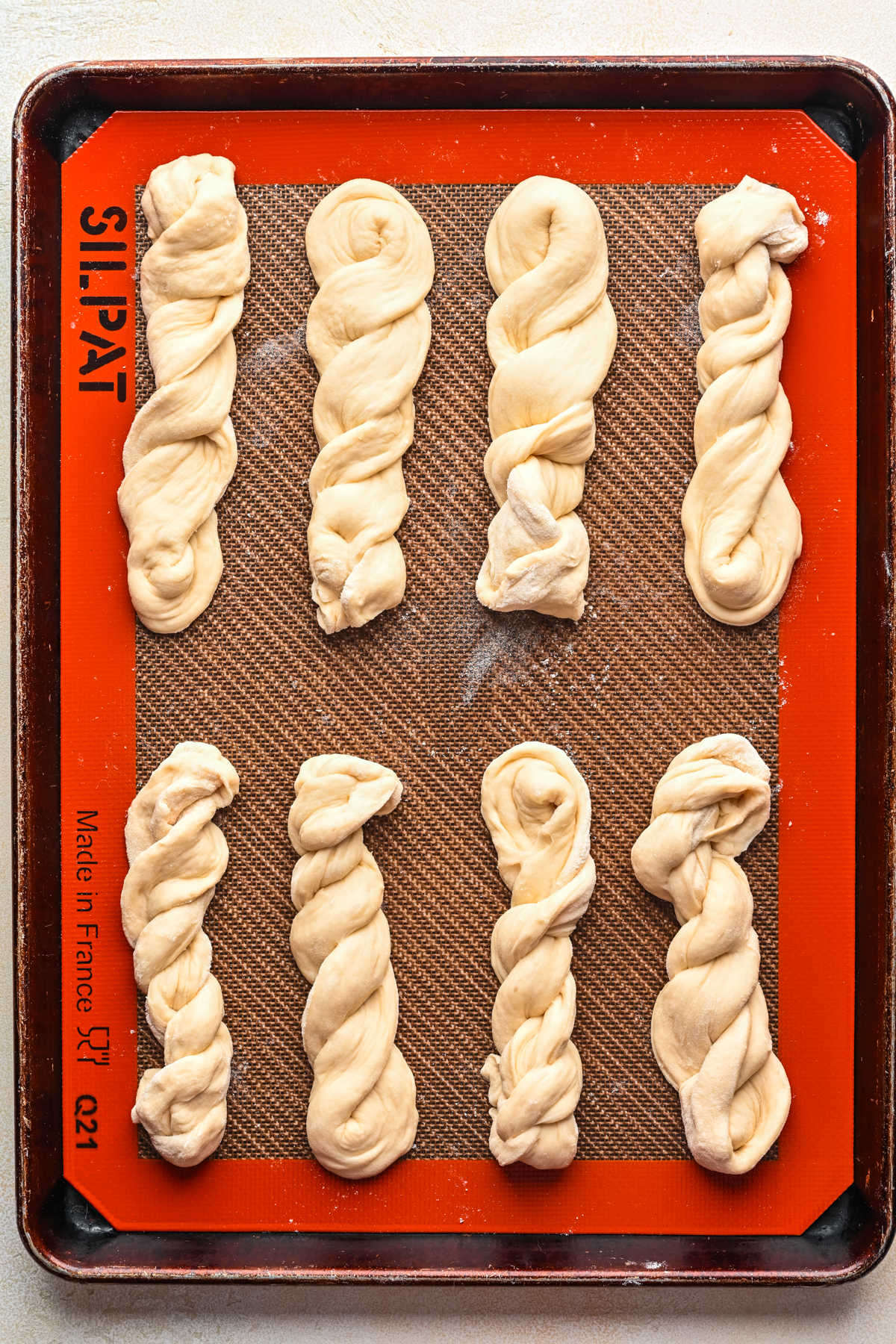 Twisted unbaked breadsticks on a baking sheet. 