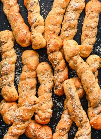 Homemade breadsticks on a piece of dark slate.