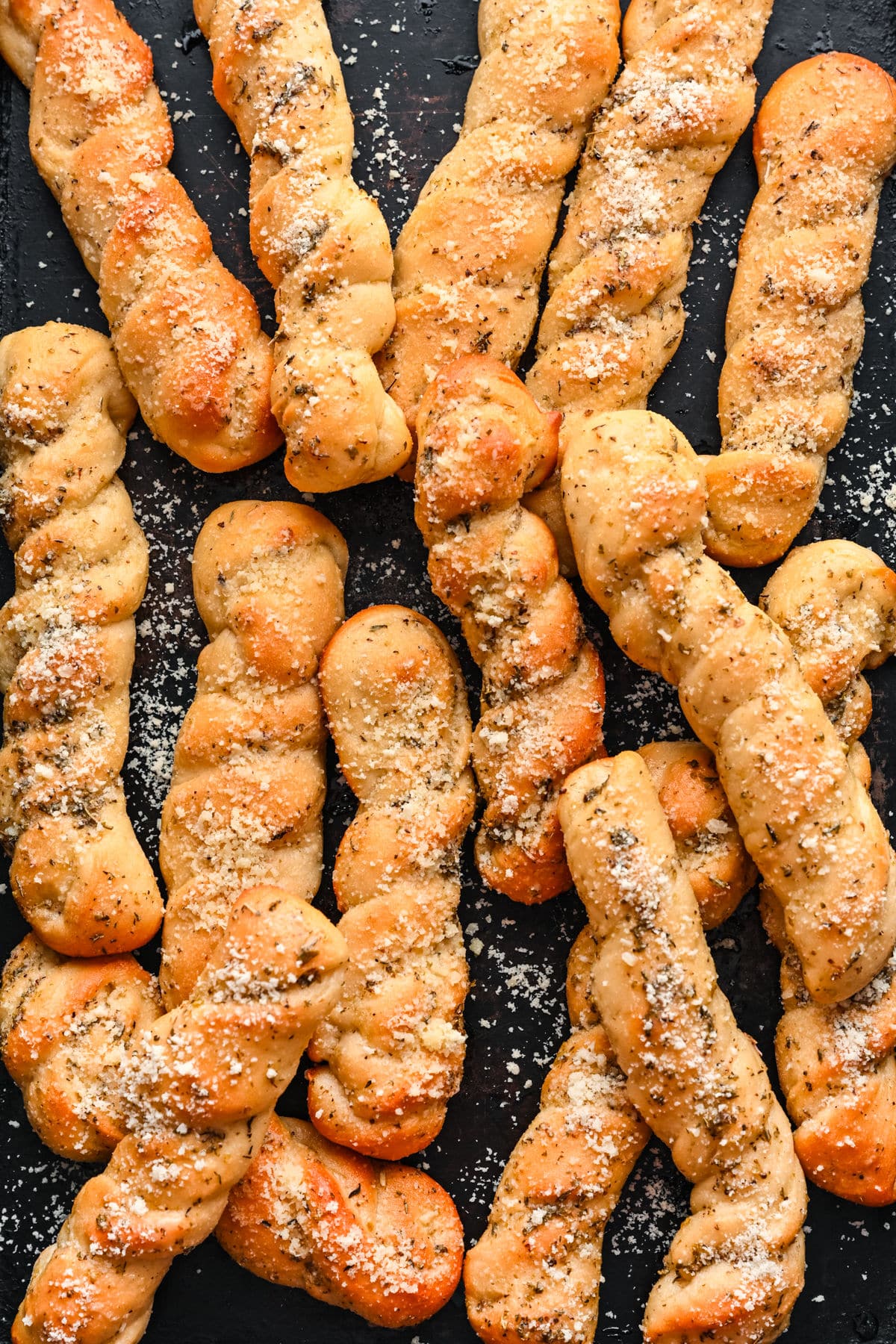 Homemade breadsticks on a piece of dark slate.