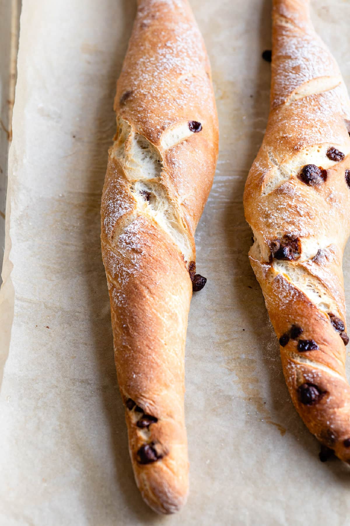 Baked chocolate chip baguettes on a piece of parchment paper.