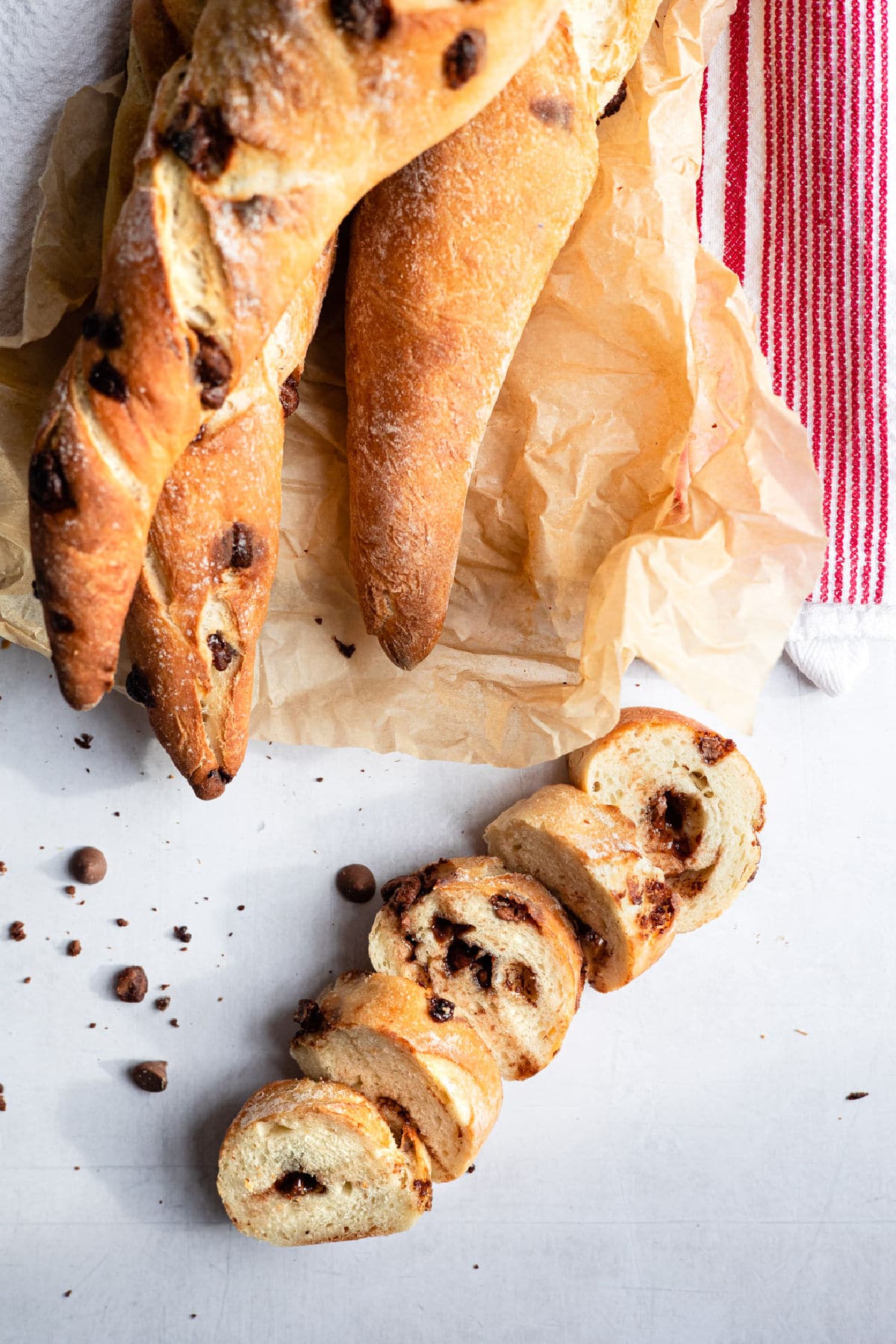 A cut chocolate chip baguette next to several baked baguettes.