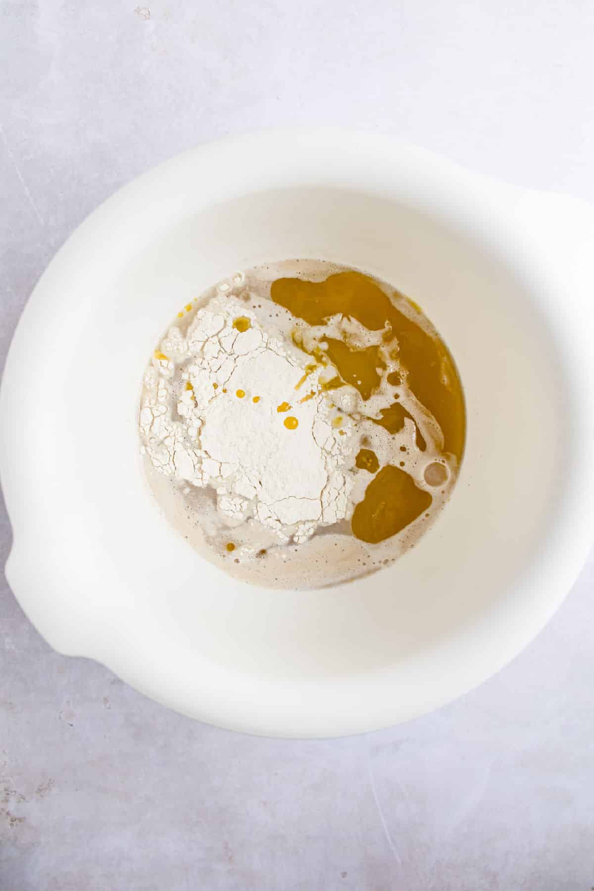 Oil flour and yeast mixture in a white mixing bowl. 