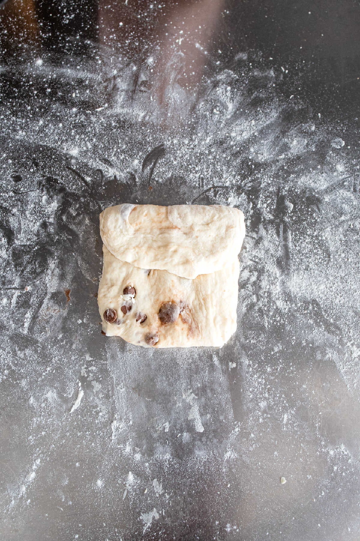 Rectangular chocolate chip baguette dough with the top third folded down.