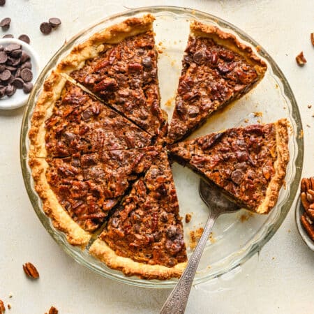 A chocolate pecan pie with a couple of slices cut from it in a glass pie pan.