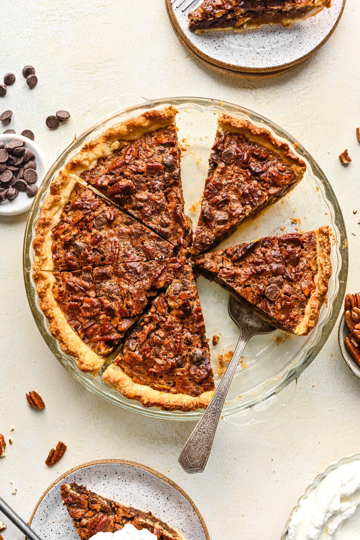 A chocolate pecan pie with a couple of slices cut from it in a glass pie pan.