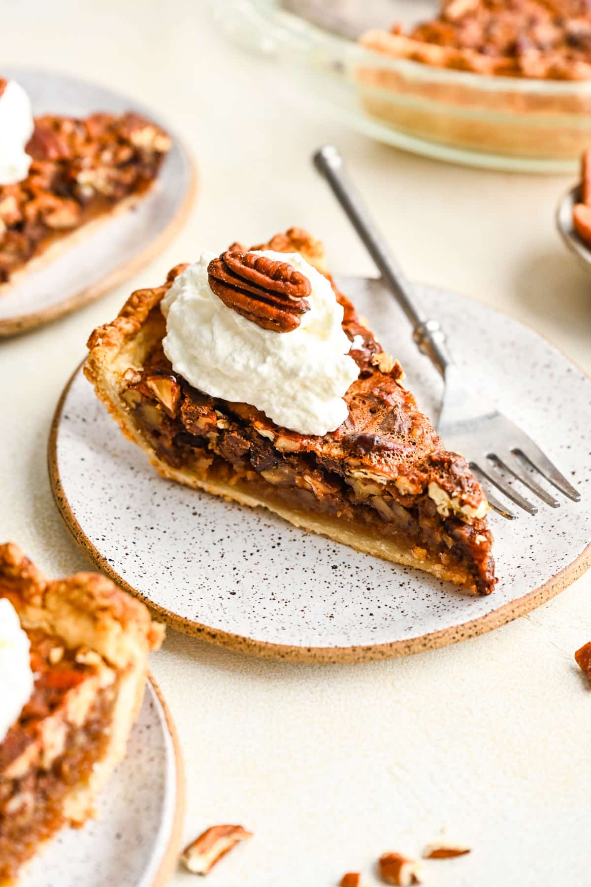 A slice of chocolate pecan pie topped with whipped cream and a pecan half.