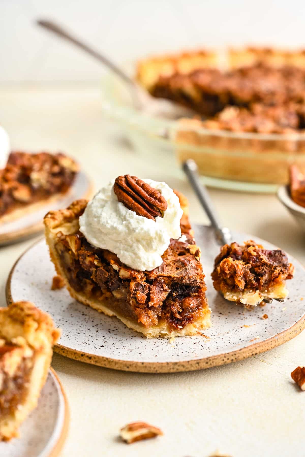 A fork with a bite of chocolate pecan pie next to the slice of pie.