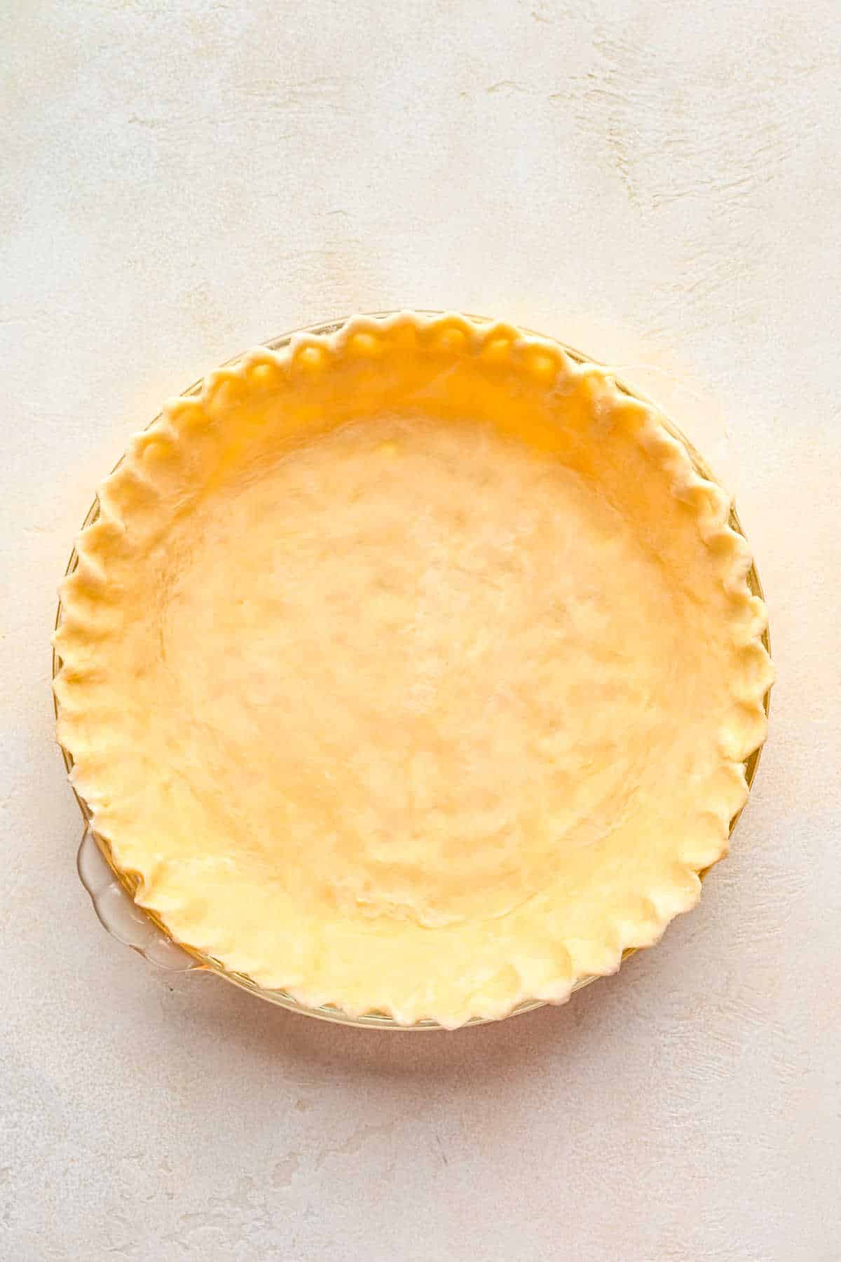Pie dough with crimped edges in a pie pan.