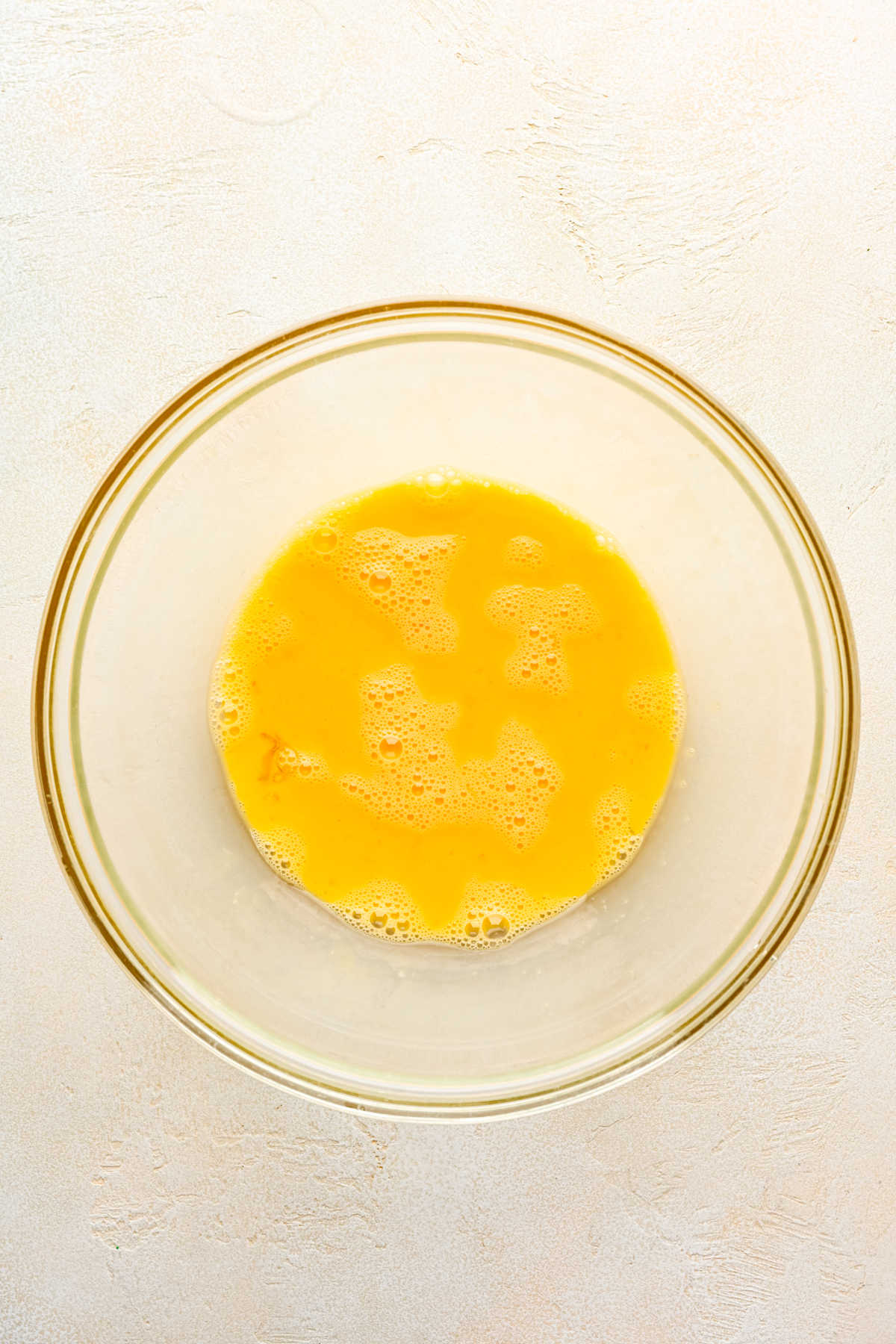 Whisked egg mixture in a glass mixing bowl.