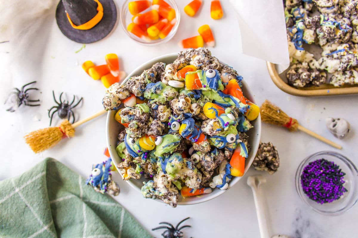 A bowl of Halloween popcorn surrounded by plastic spiders and witch hats. 