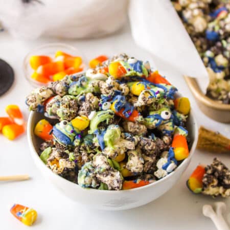 A bowl of Halloween popcorn next to plastic spiders and fake spider webs.