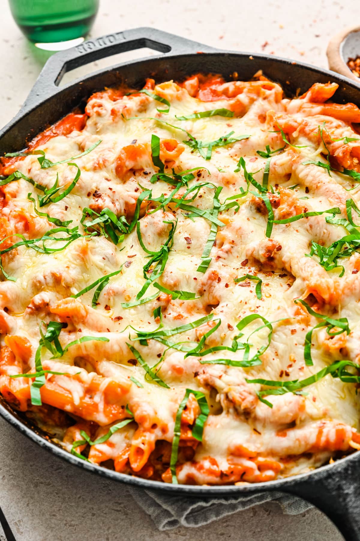 Close up photo of baked ziti in a cast iron skillet. 