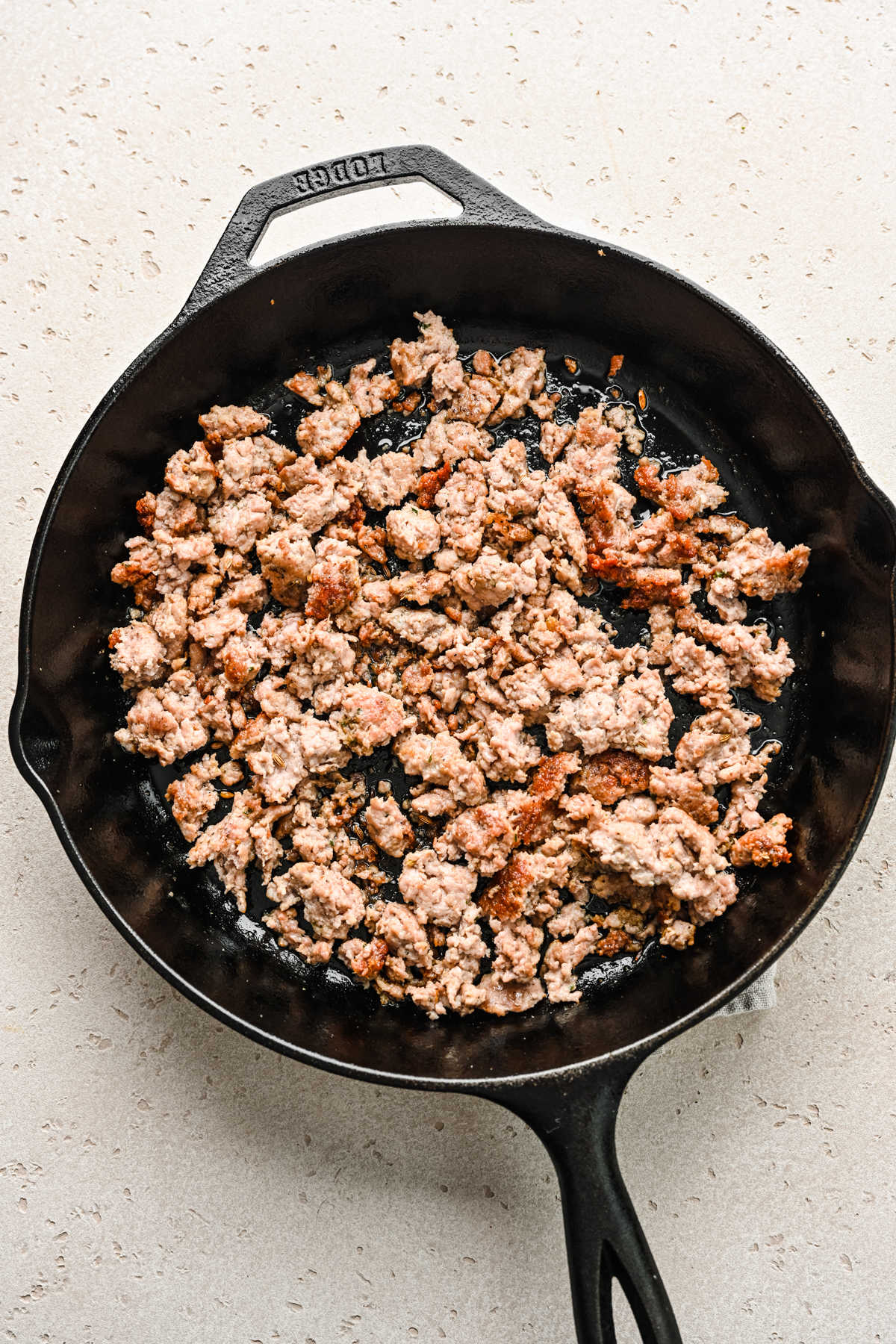Browned ground Italian sausage in a cast iron skillet.