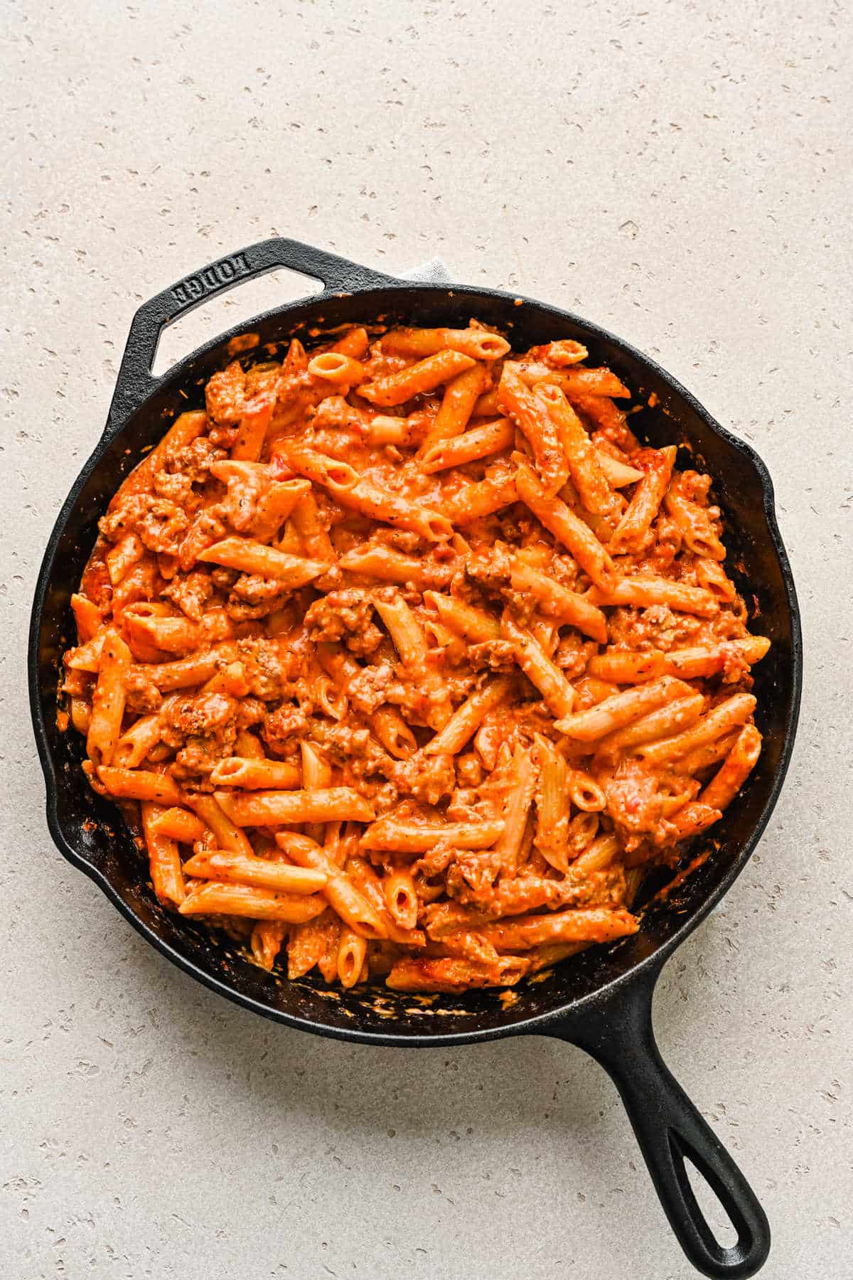 Cooked ziti and tomato sauce in cast iron skillet.