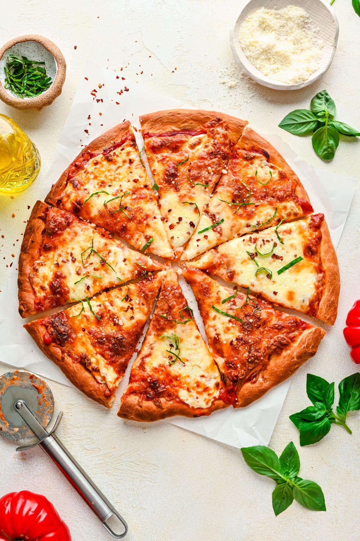 A cheese pizza made from homemade pizza dough next to a pizza cutter. 