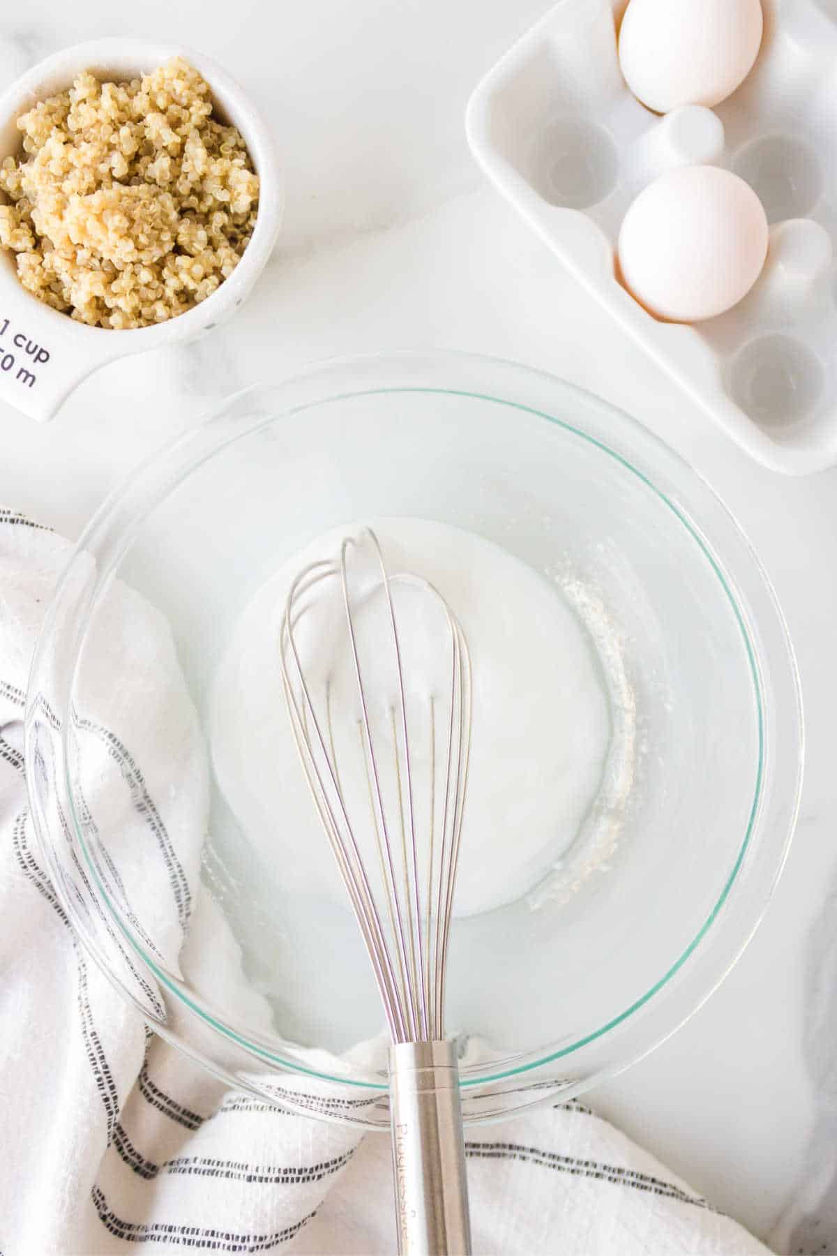 Melted coconut oil and Greek yogurt whisked together in a glass mixing bowl. 