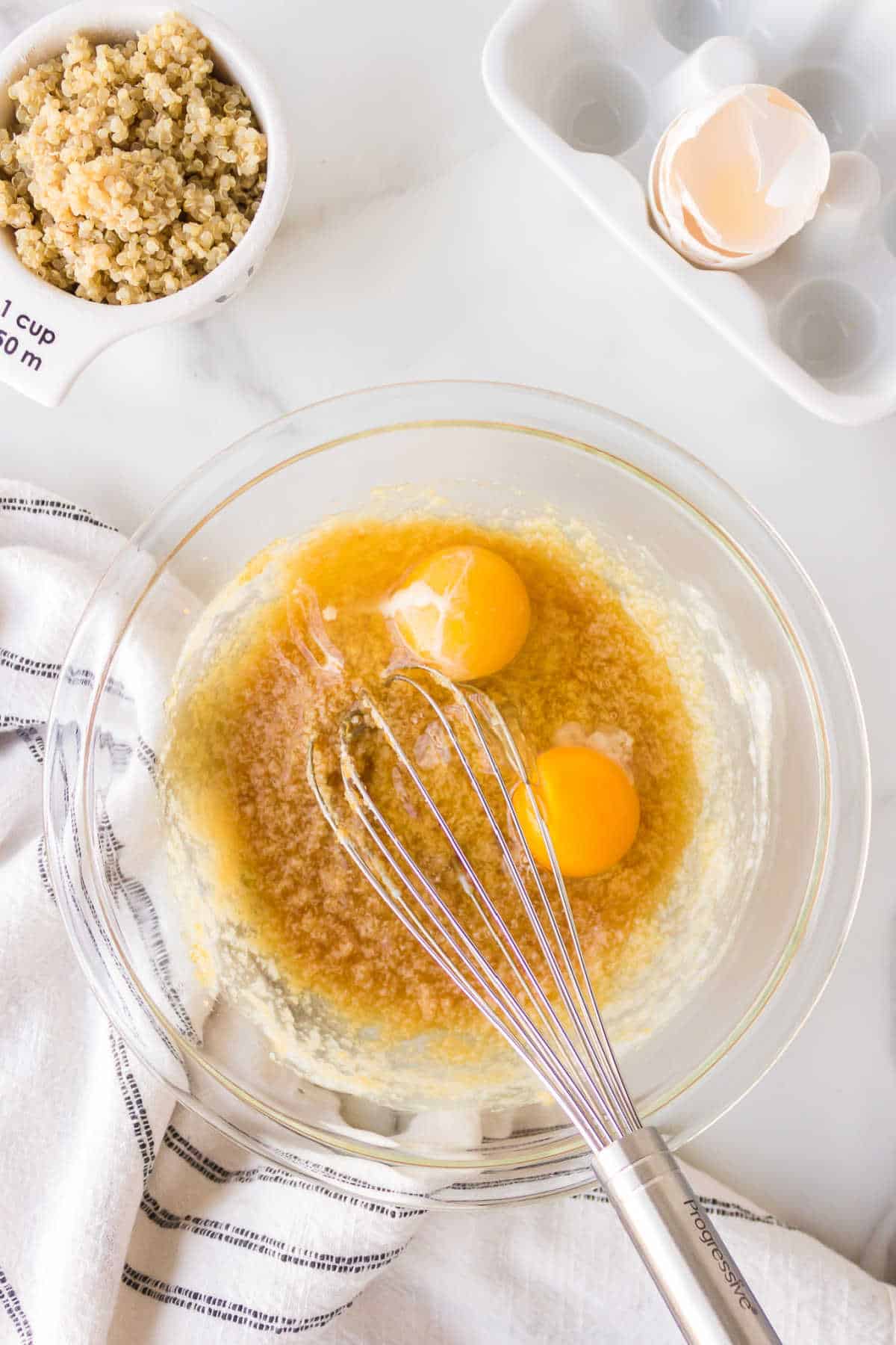 Two eggs in brown sugar mixture in a glass mixing bowl. 
