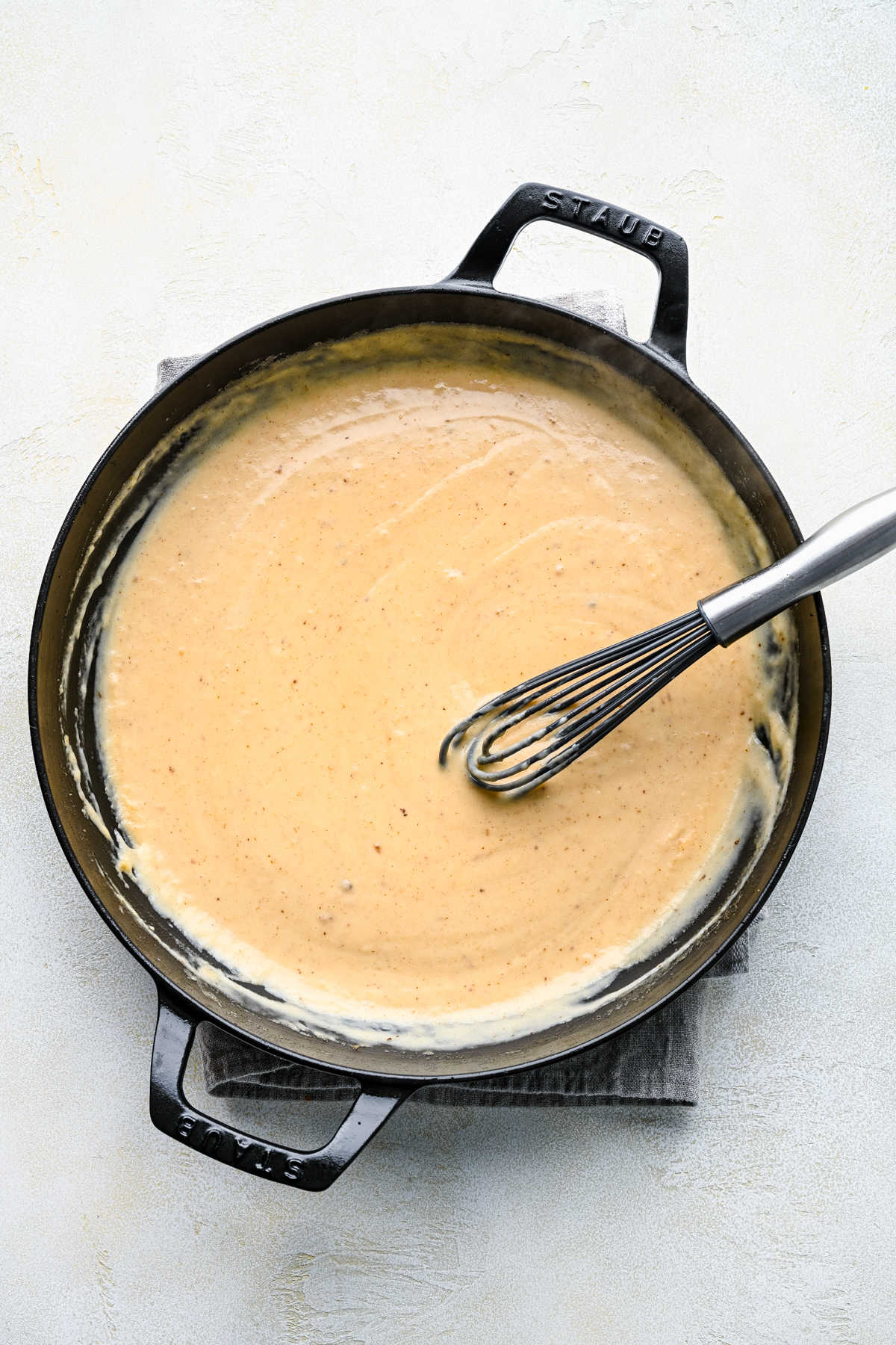 Thickened stock and cream mixture in a cast iron skillet. 