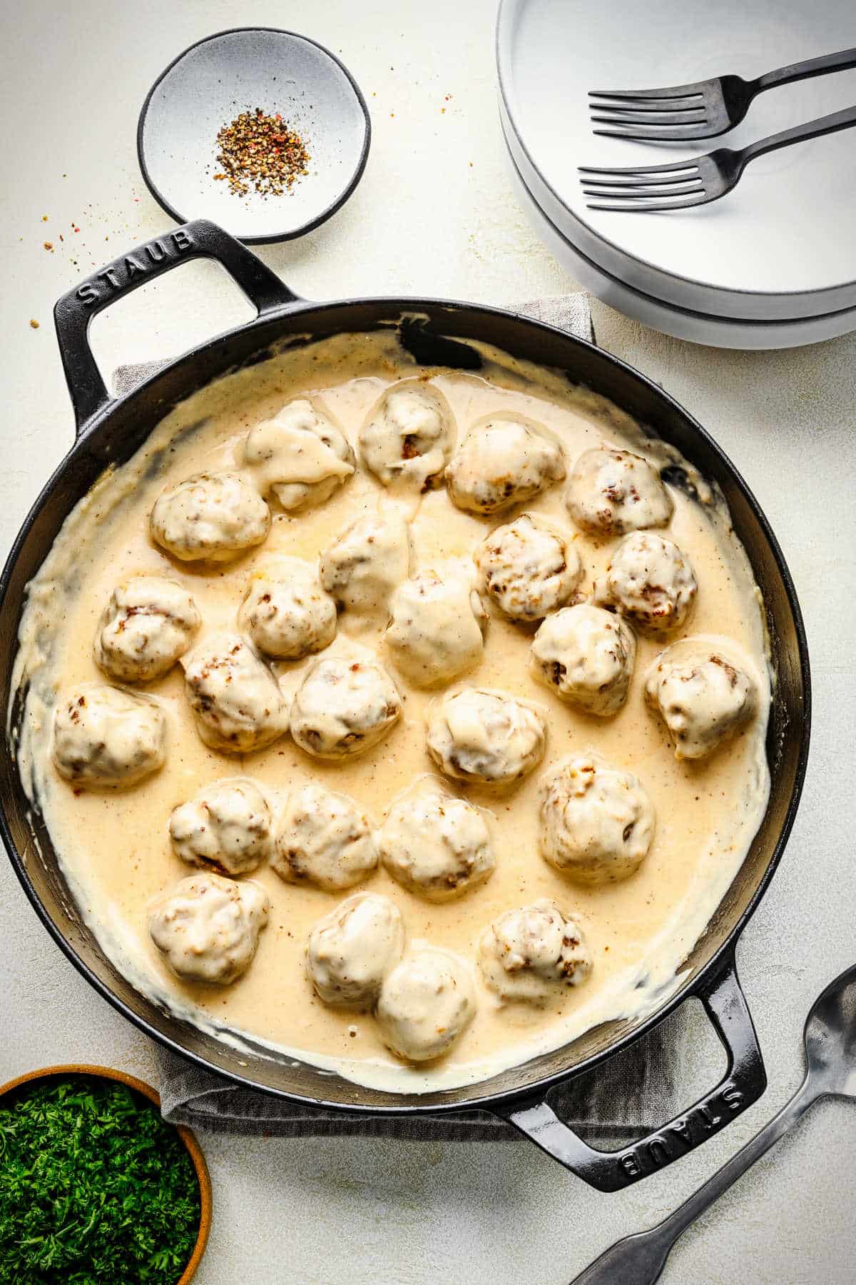 Cooked Swedish meatballs in cream sauce in a cast iron skillet.