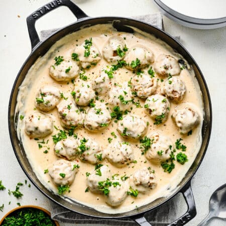 A cast iron pan filled with Swedish meatballs and cream sauce.