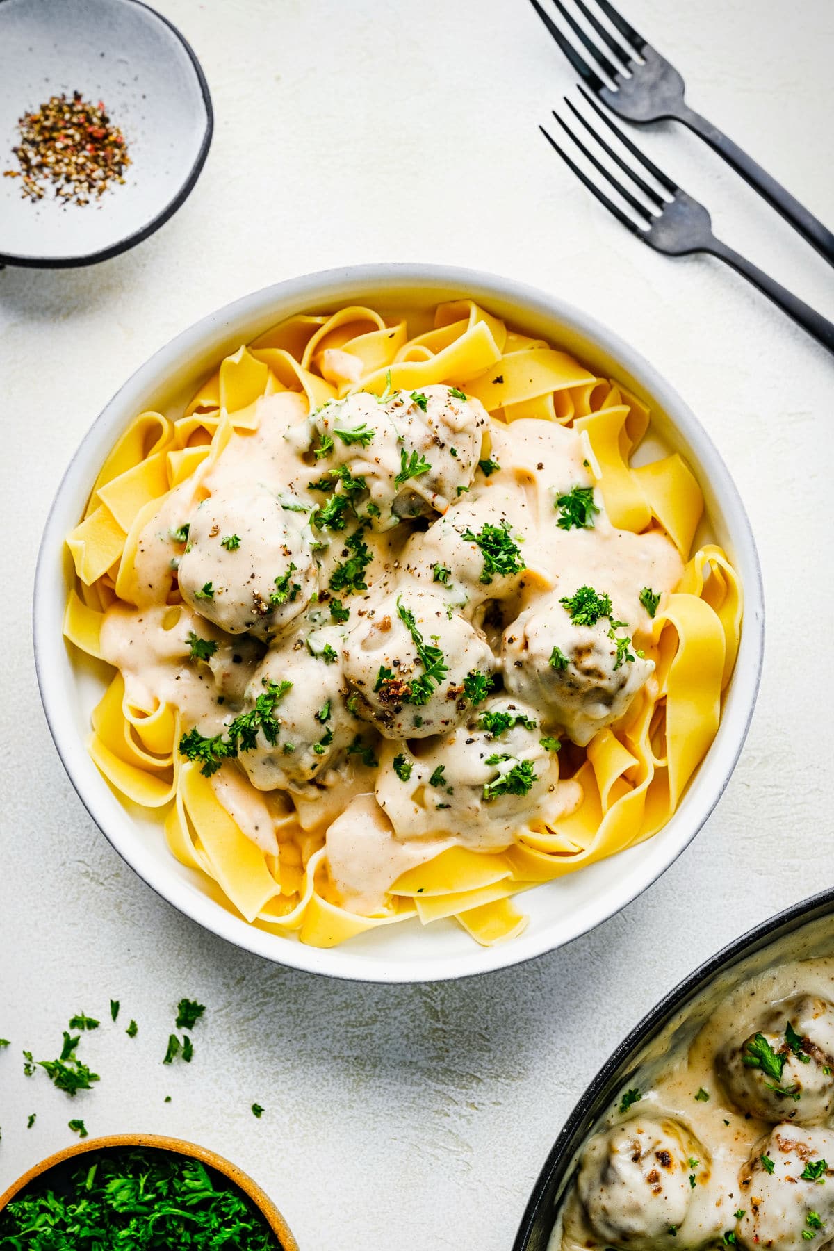 Swedish meatballs over egg noodles in a white bowl.
