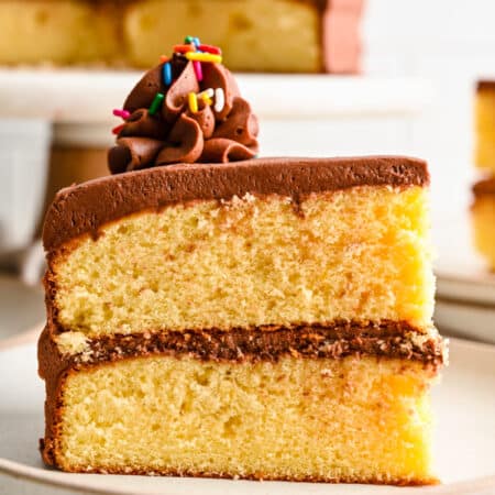 A slice of homemade yellow cake with two layers on a white plate.