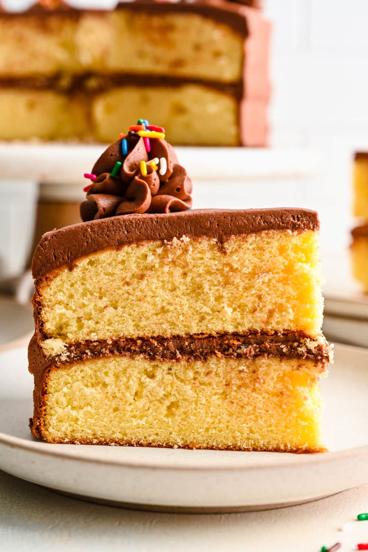 A slice of homemade yellow cake with two layers on a white plate.