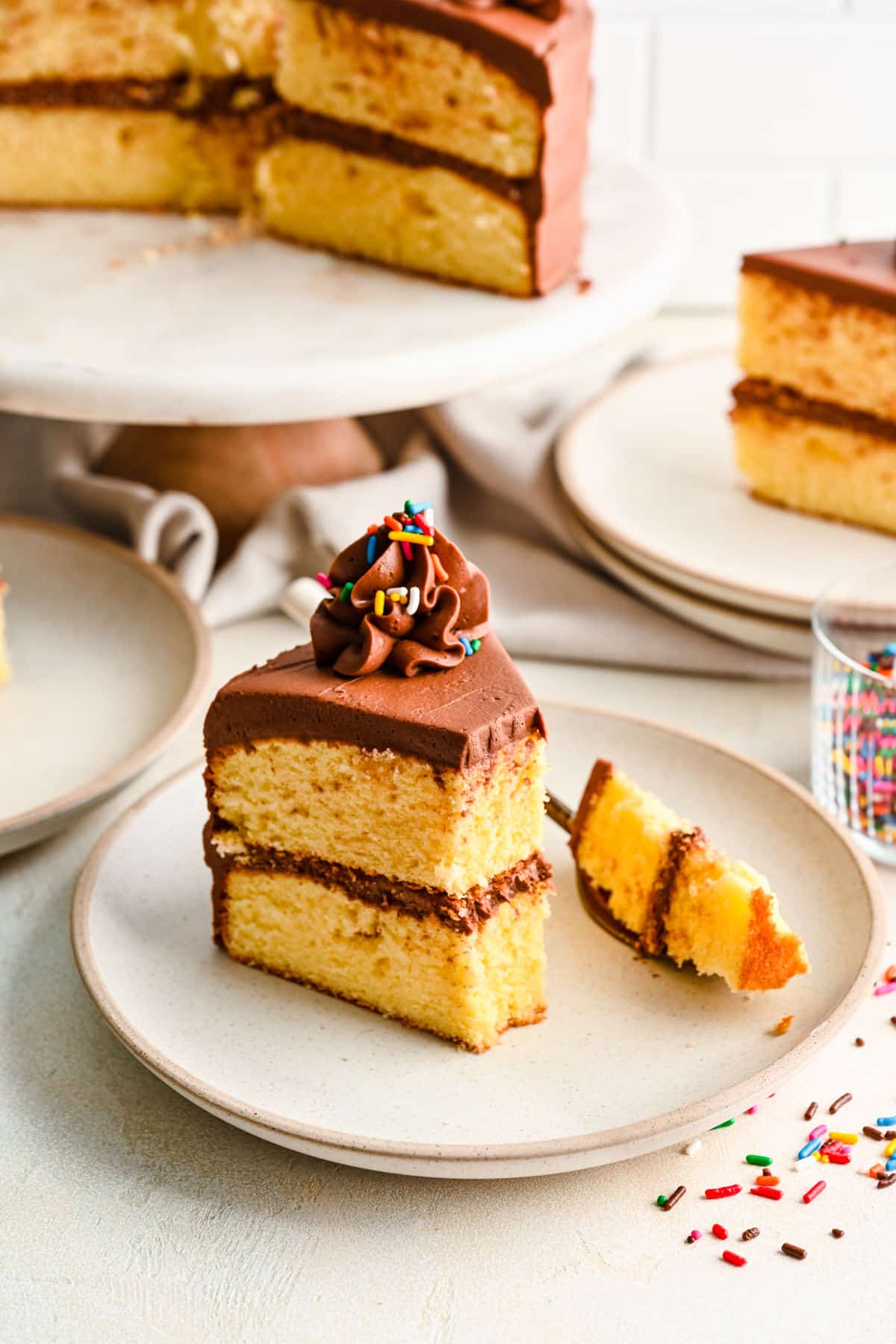A slice of homemade yellow layer cake with a bite on a fork. 