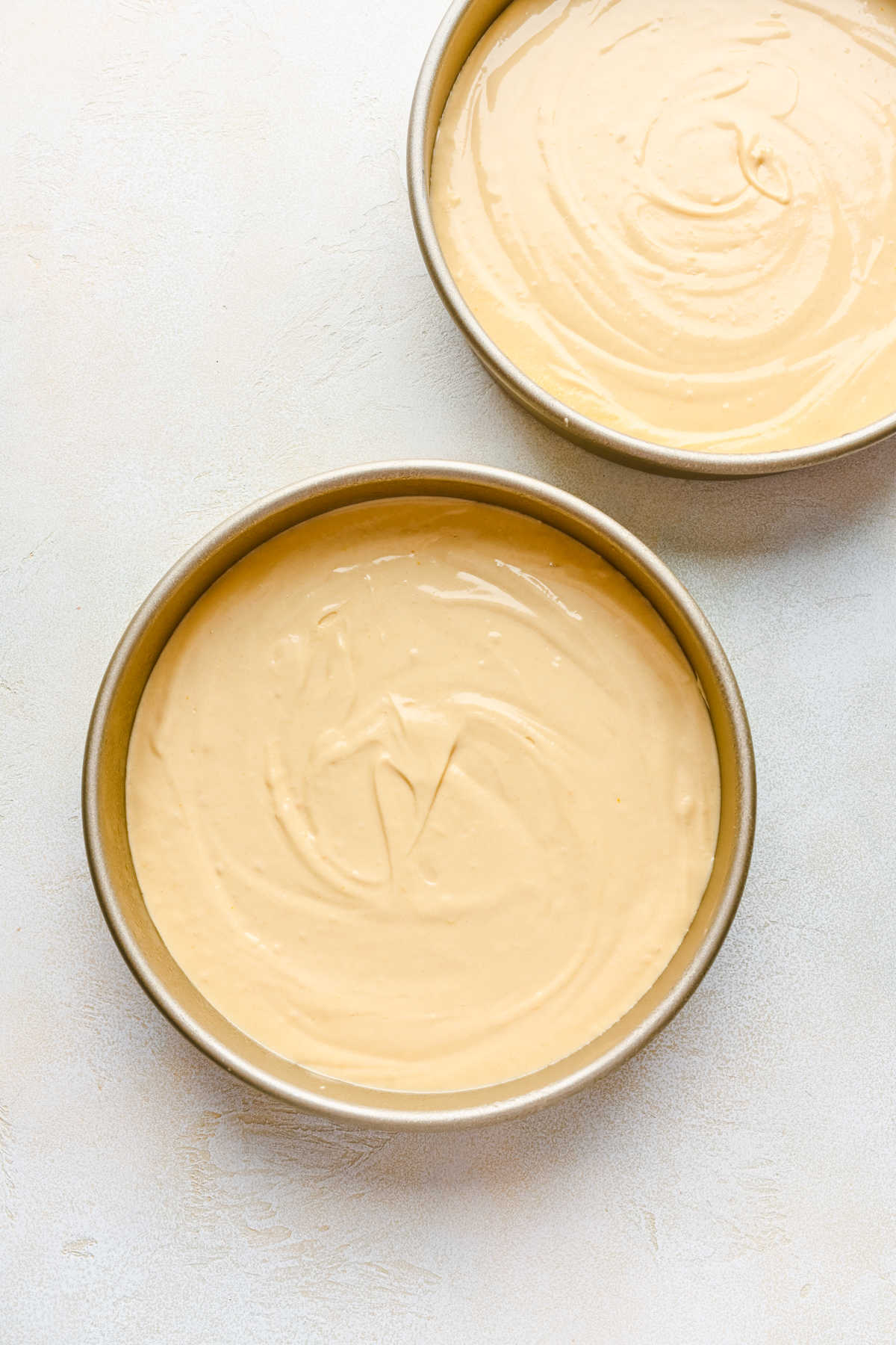 Yellow cake batter in two round cake pans. 