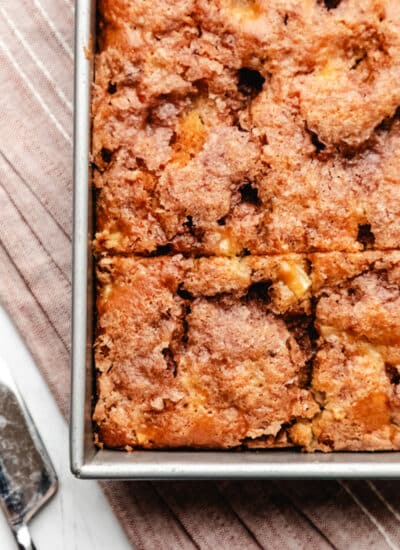 A piece of cake cut in a cinnamon apple cake next to a cake knife.
