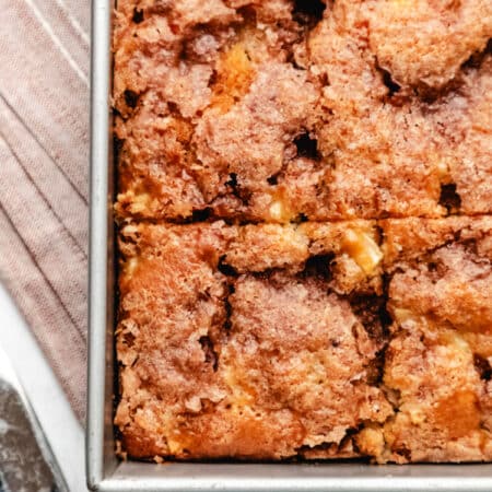 A piece of cake cut in a cinnamon apple cake next to a cake knife.