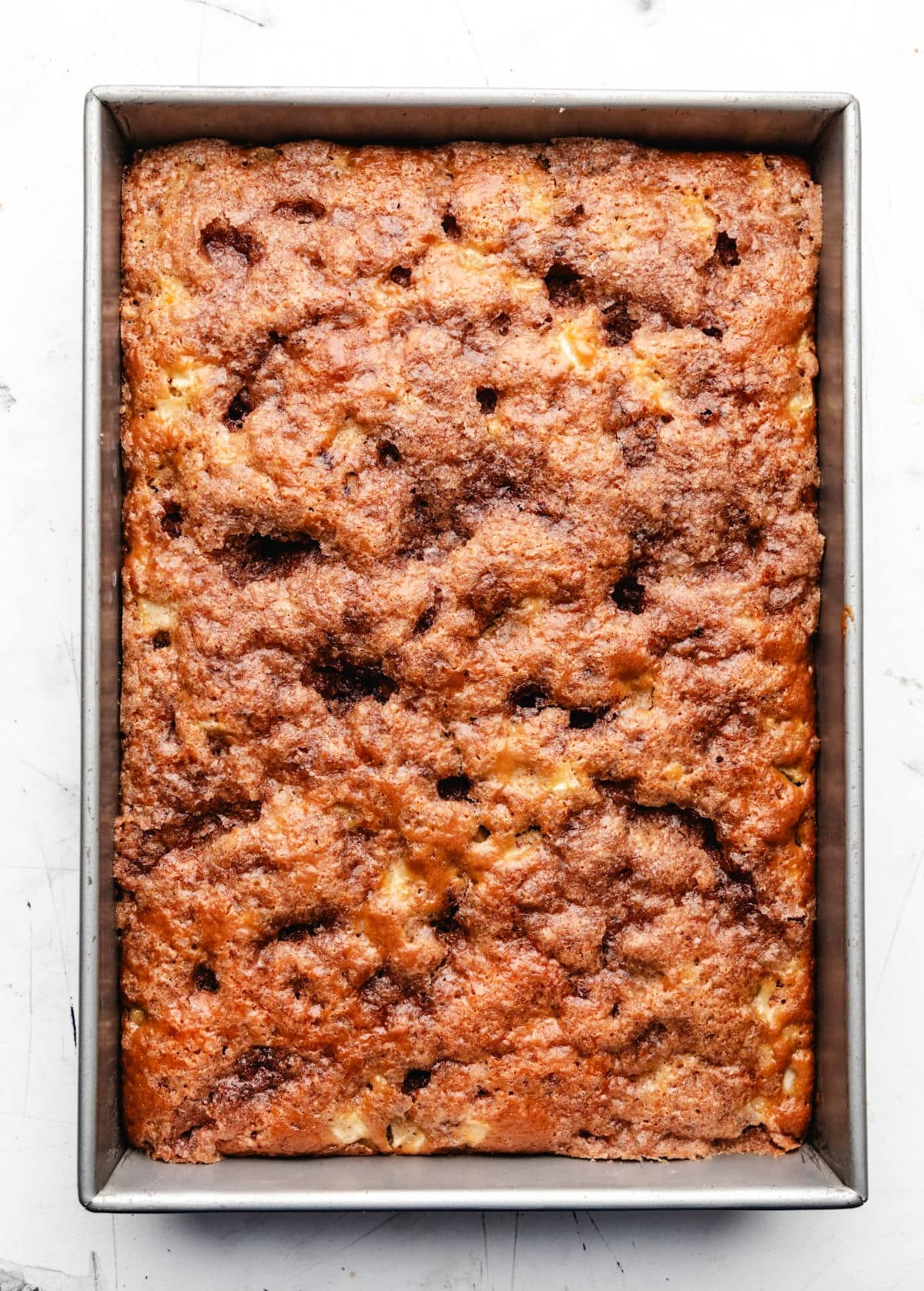 A baked cinnamon apple cake in a metal pan. 