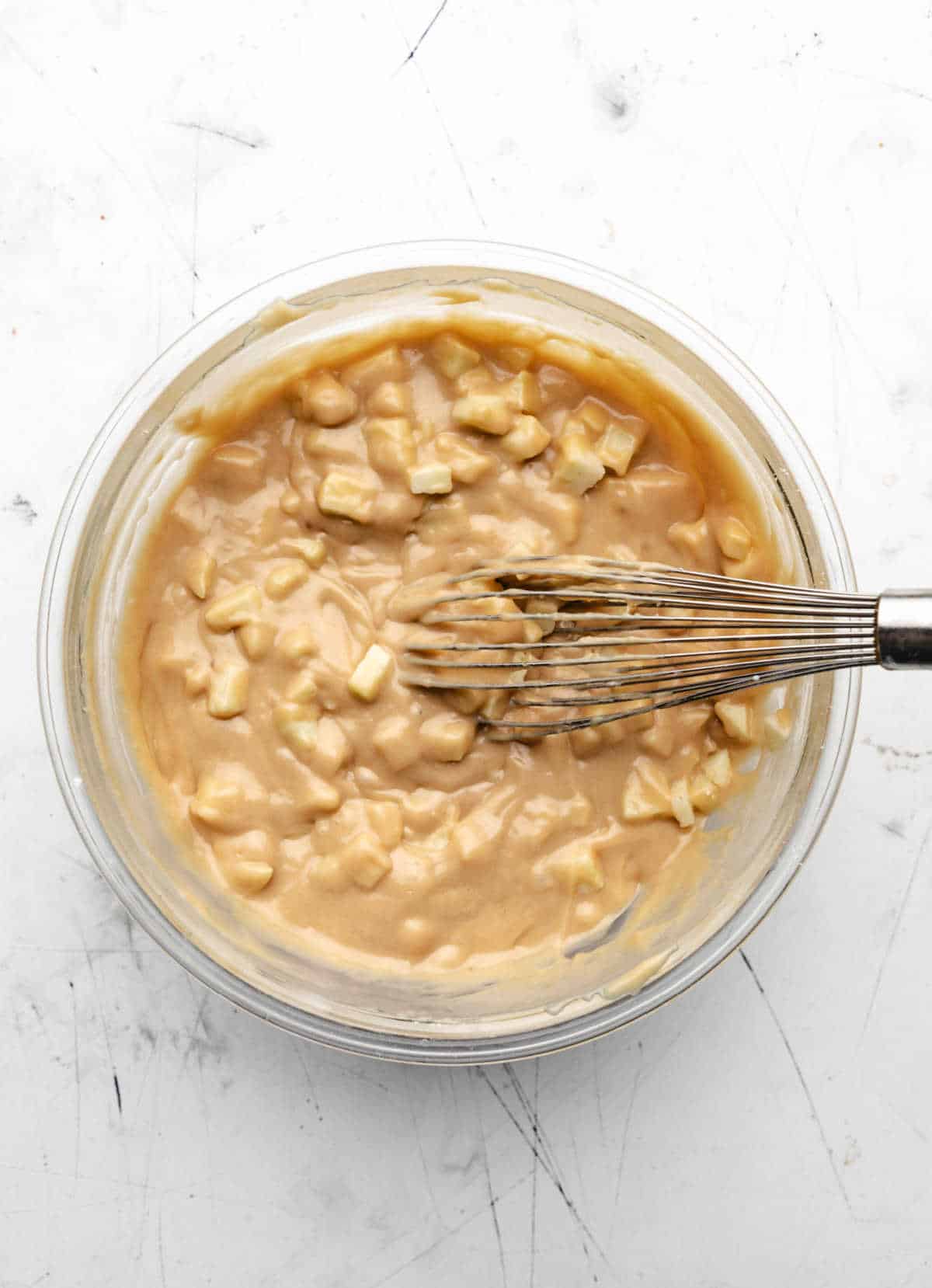 Cinnamon apple cake batter in a glass mixing bowl. 
