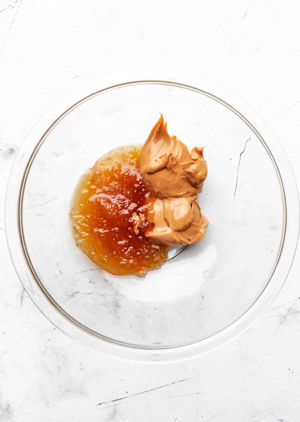 Honey and peanut butter in a glass mixing bowl. 