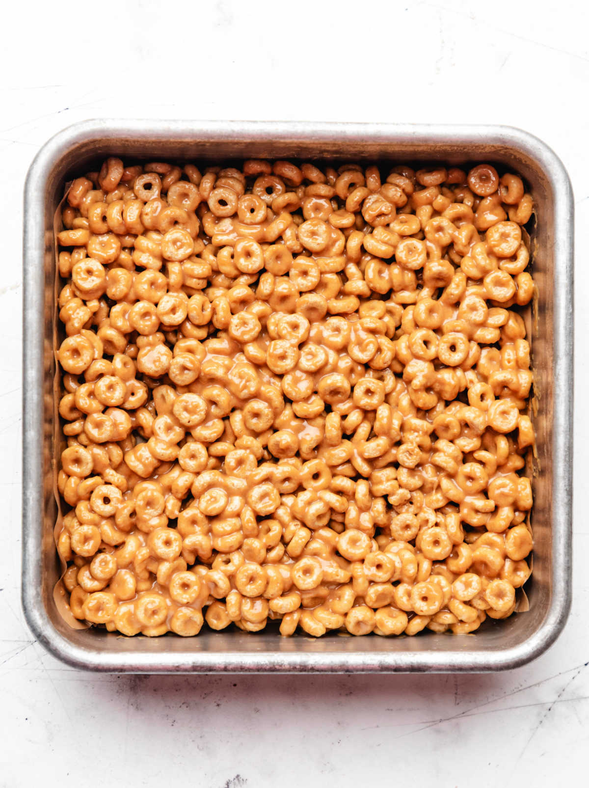 Peanut butter cheerio bars in a square metal baking pan. 
