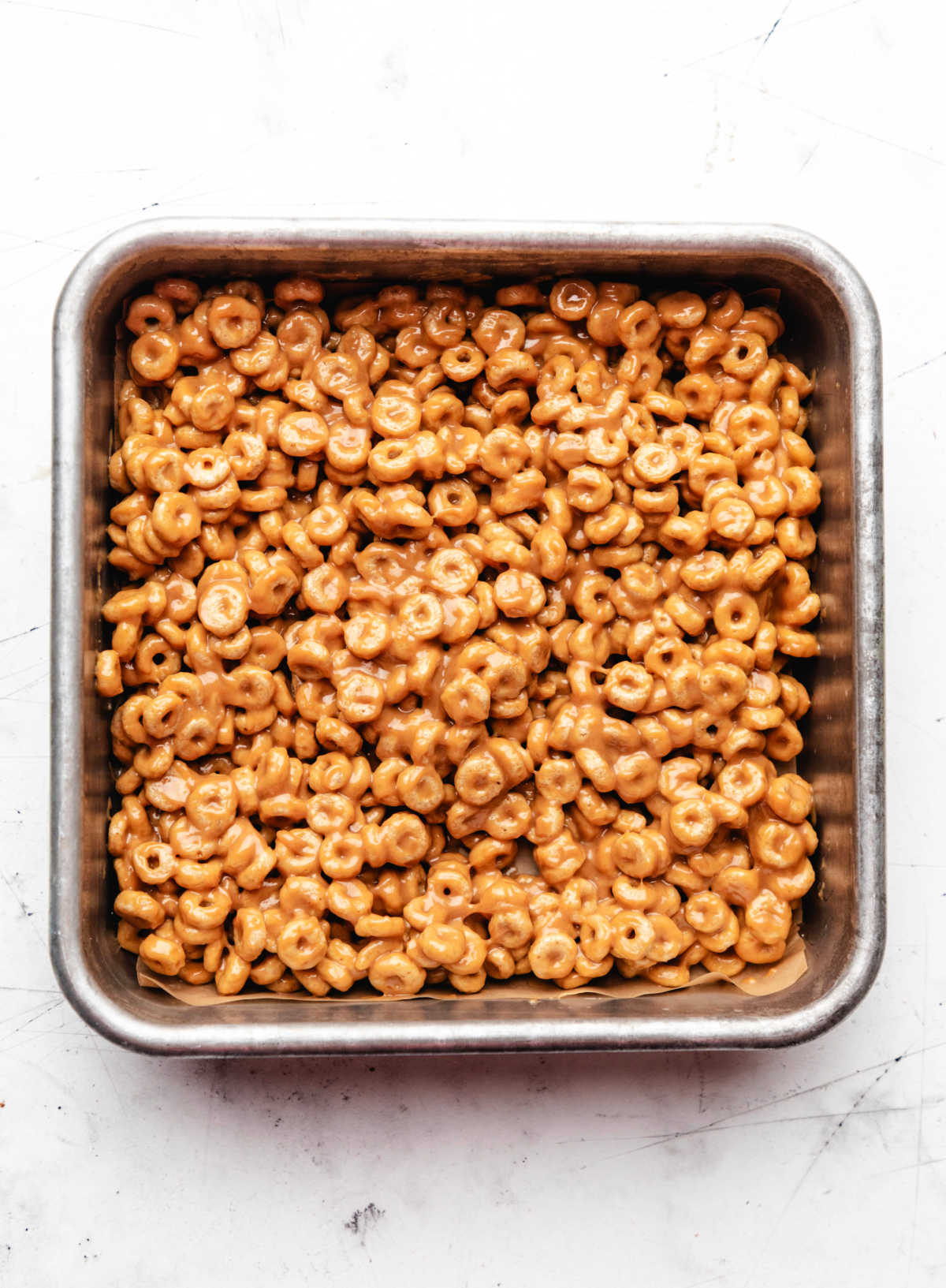 Frozen cheerio bar mixture in a metal baking pan.