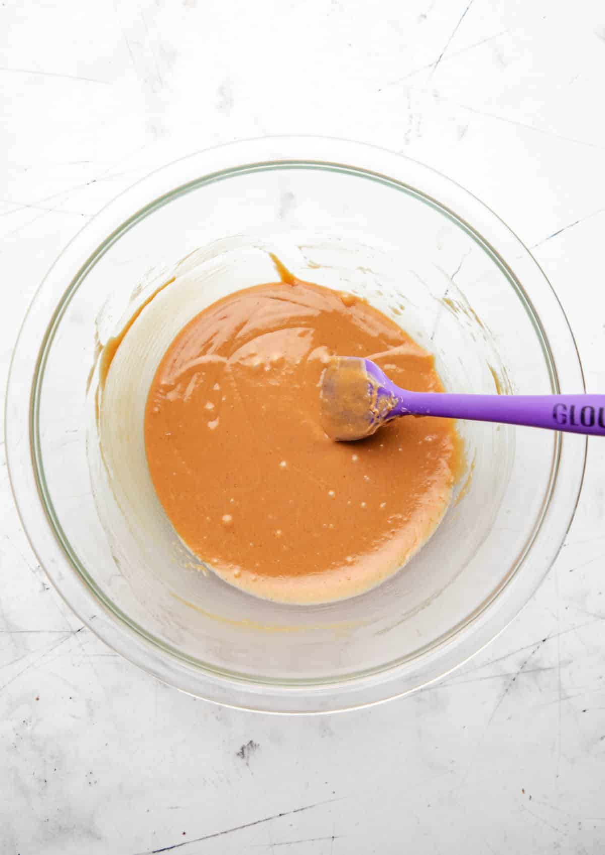 Melted peanut butter and honey in a glass mixing bowl. 