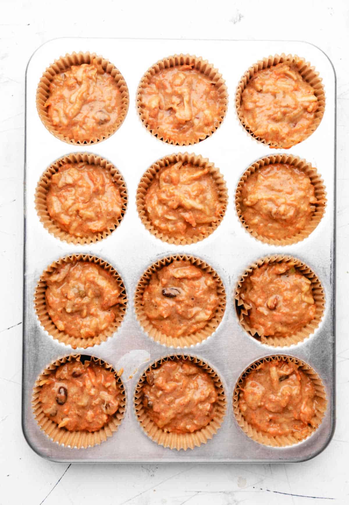 Morning glory muffin batter in a muffin tin. 