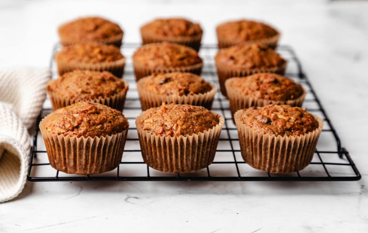 A dozen morning glory muffins on a black wire cooling rack.