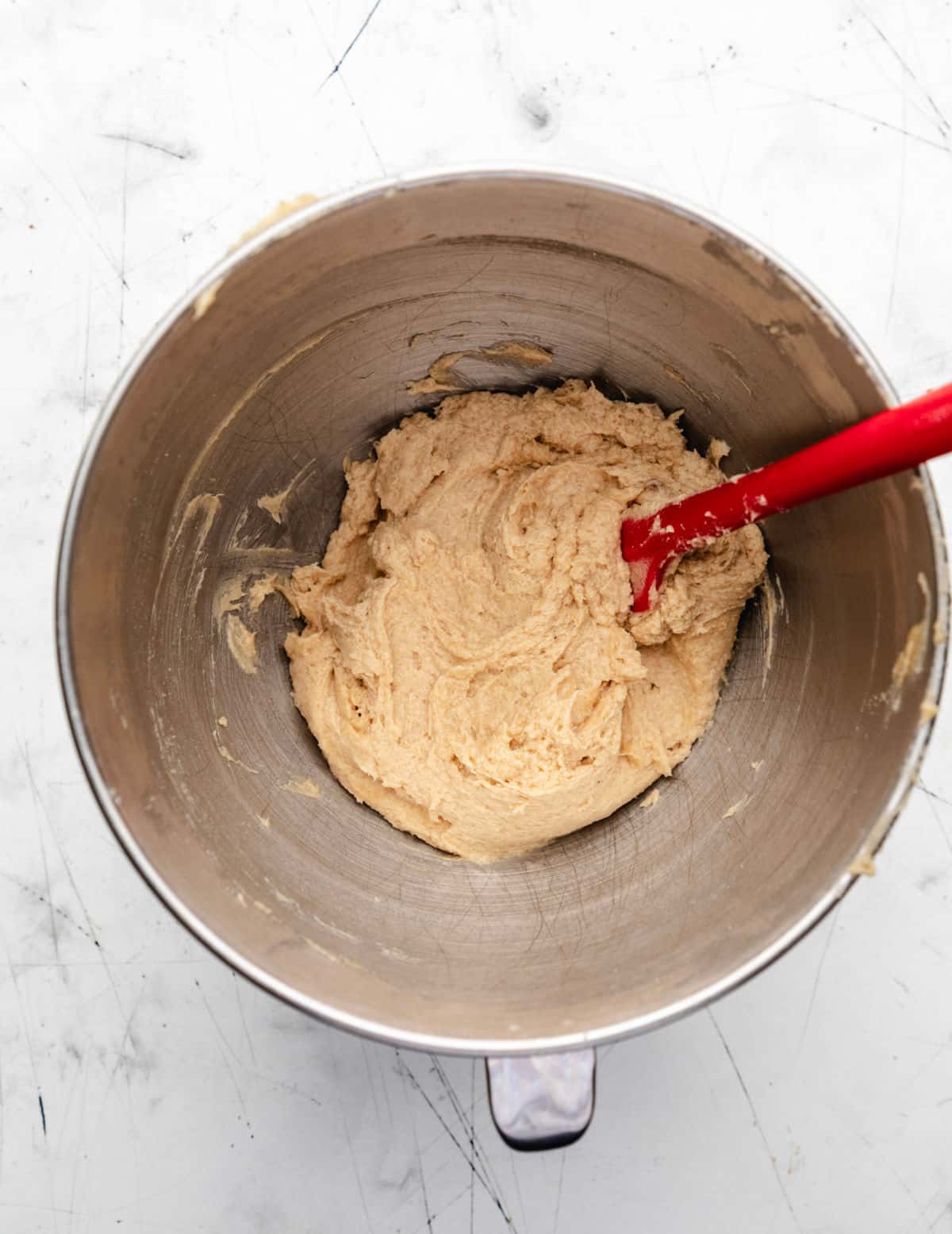 Eggs beaten into creamed butter and sugar mixture in a silver mixing bowl. 