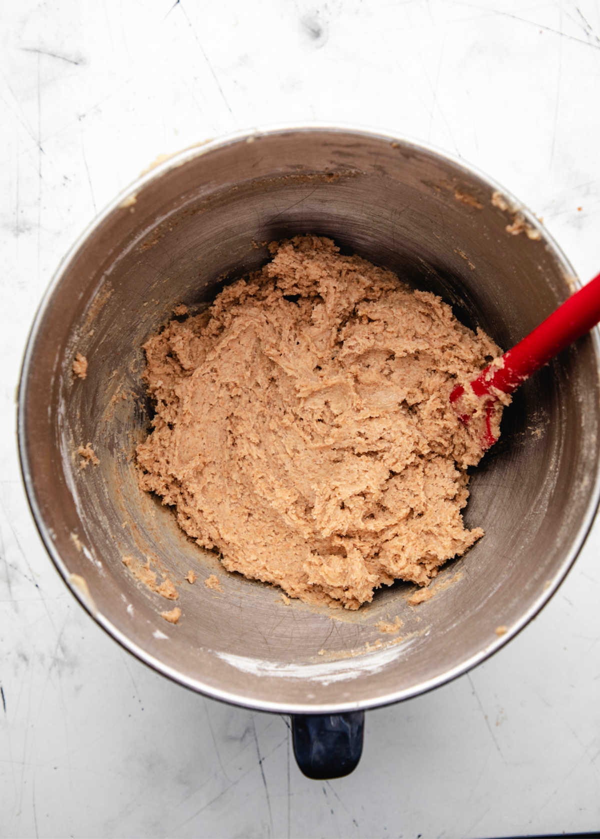 Whole wheat chocolate chip cookie dough without chocolate in a silver mixing bowl. 