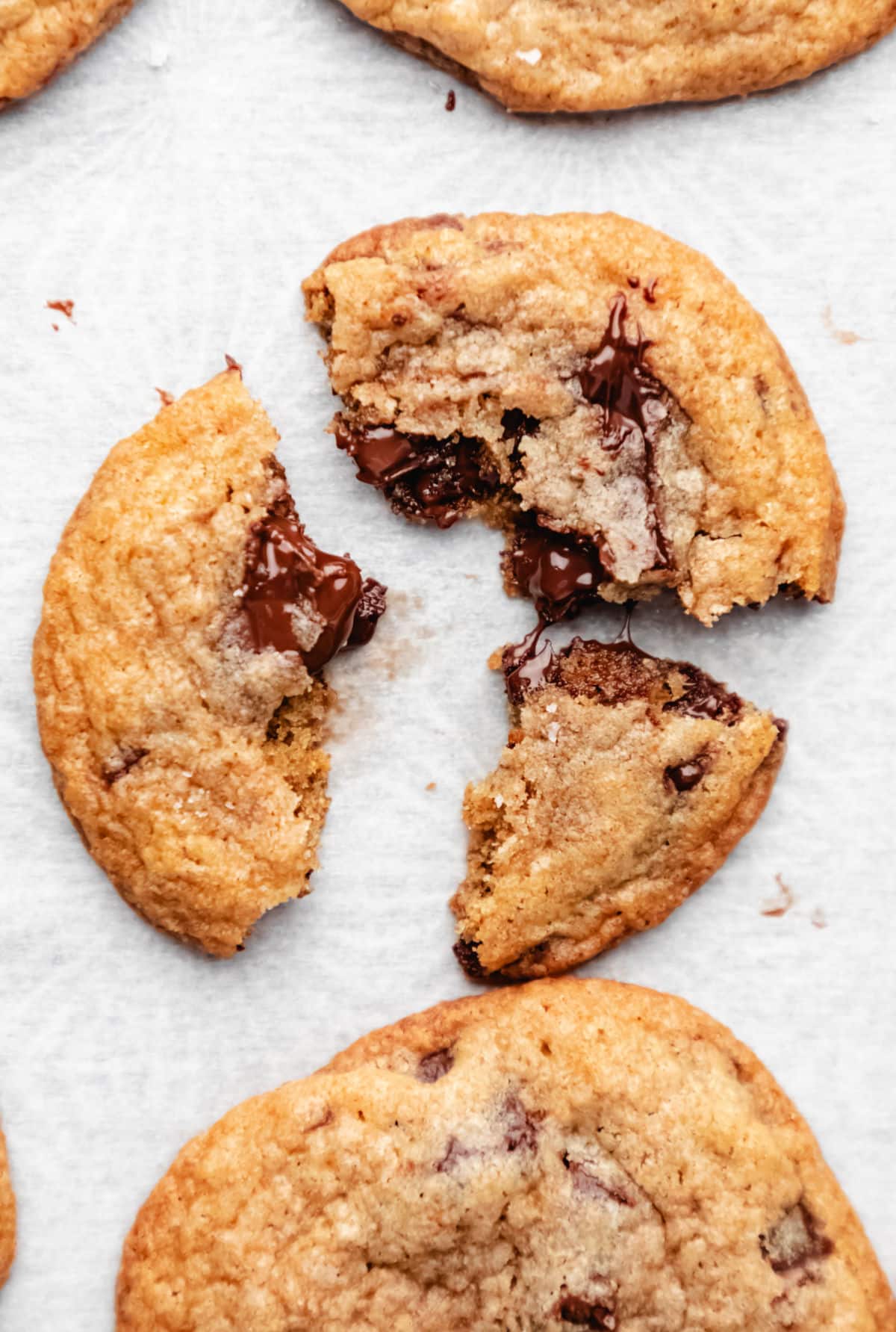 A whole wheat chocolate chip cookie broken into three pieces. 