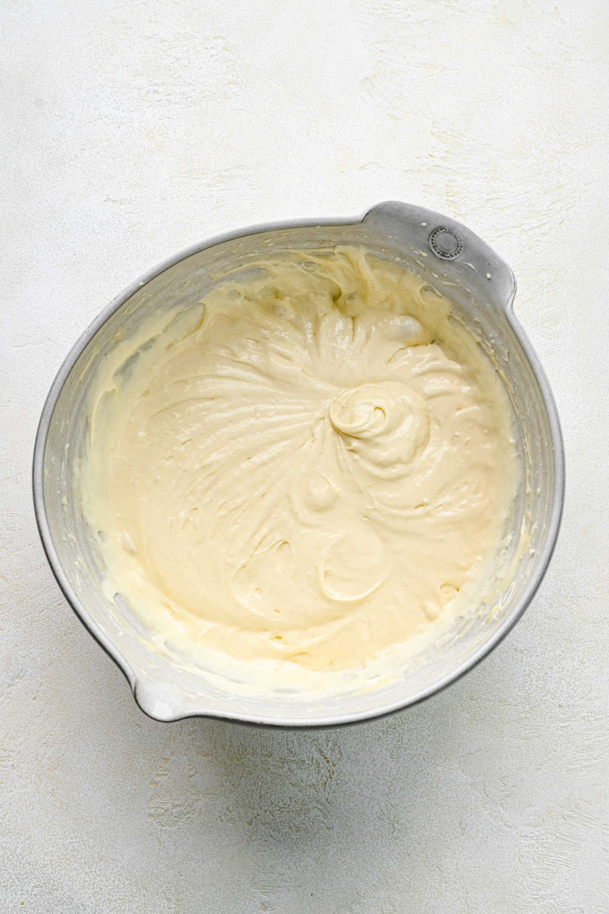 Cinnamon roll poke cake batter in a ceramic mixing bowl. 