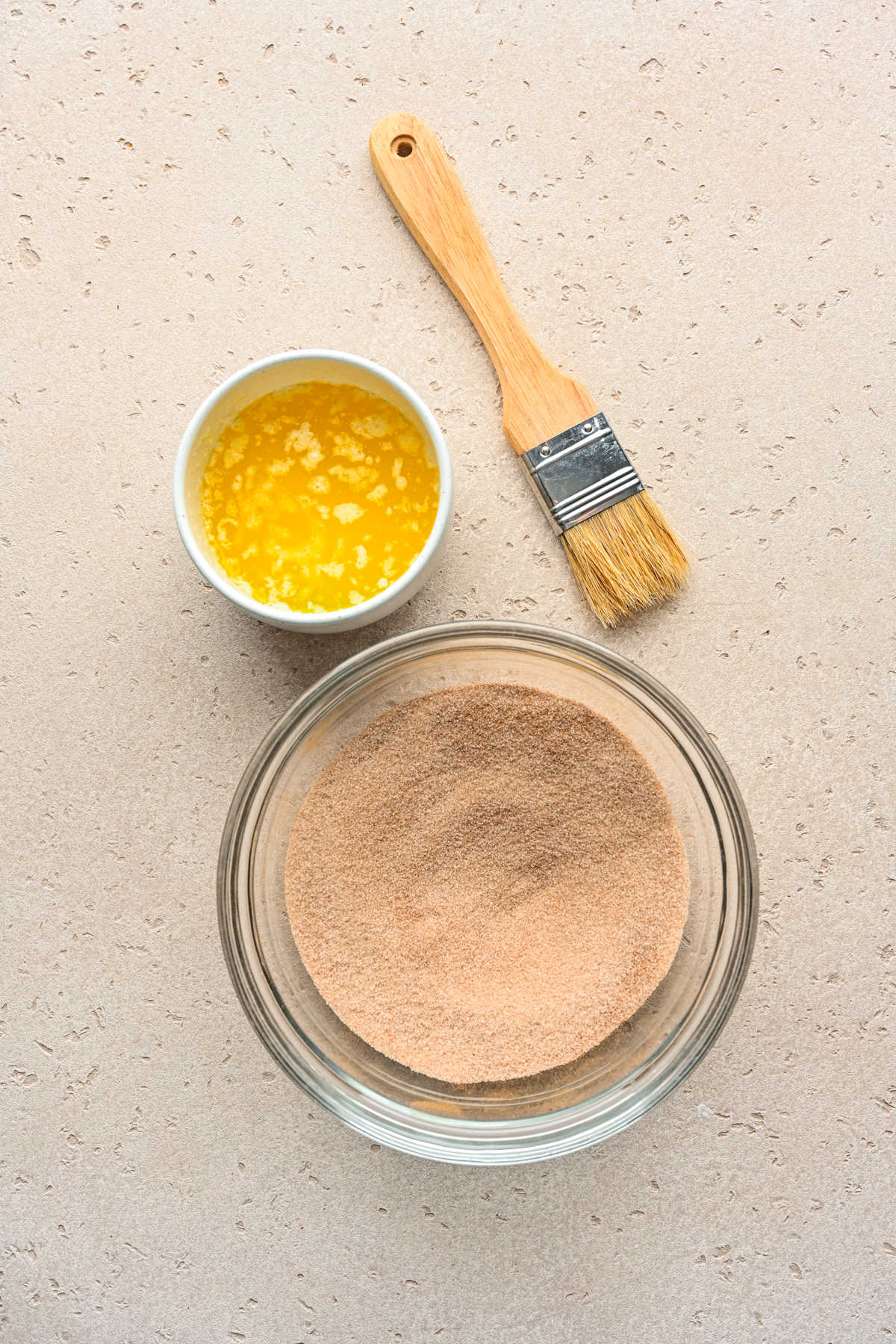 A dish of cinnamon sugar next to a dish of melted butter.